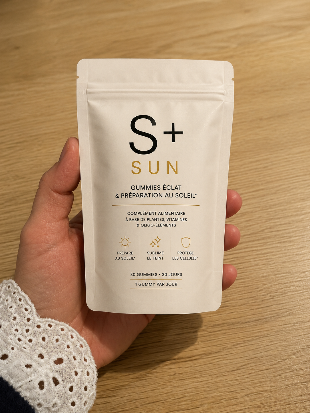 S+ SUN pouch held above a wooden table